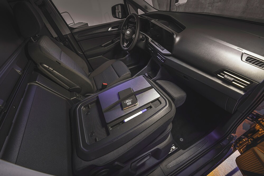 Interiér Ford Transit Connect s palubní deskou, sedadly, notebookem a telefonem na středové konzole.