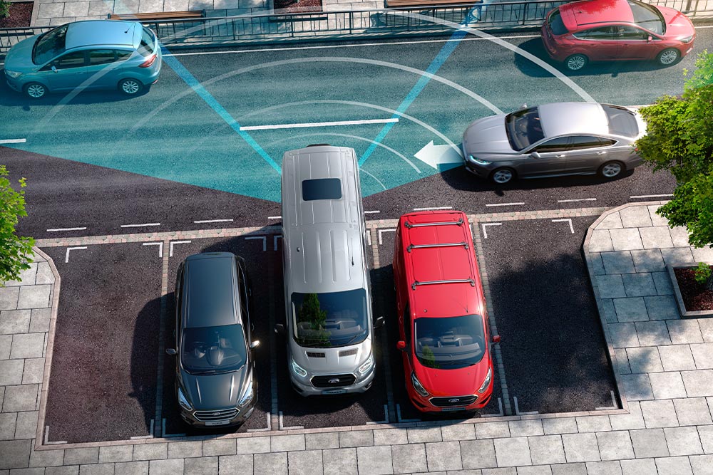 Stříbrný Ford Transit Van při couvání s modrými liniemi znázorňujícími použití zadních parkovacích senzorů.