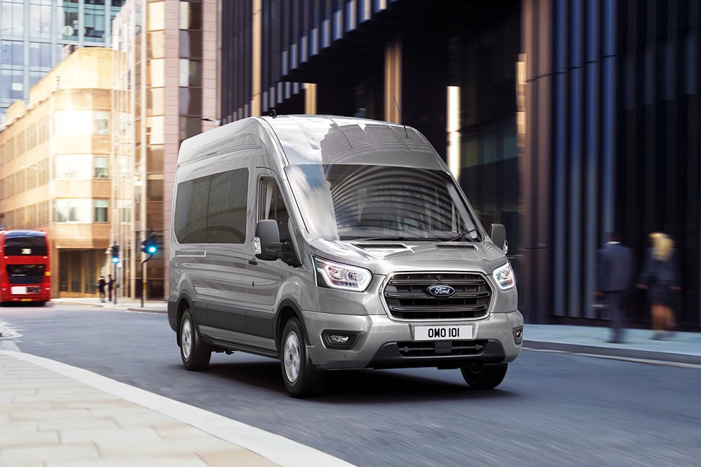 Ford Transit Kombi jedoucí po městě.