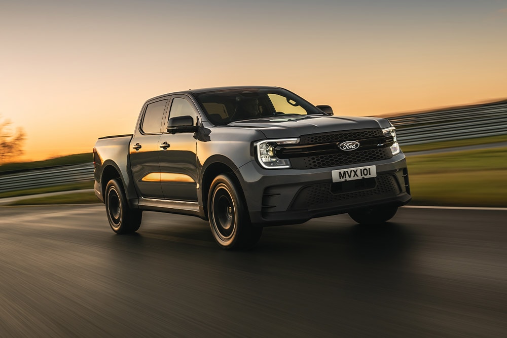 Tmavě šedý Ford Ranger Platinum jedoucí po cestě při západu slunce.