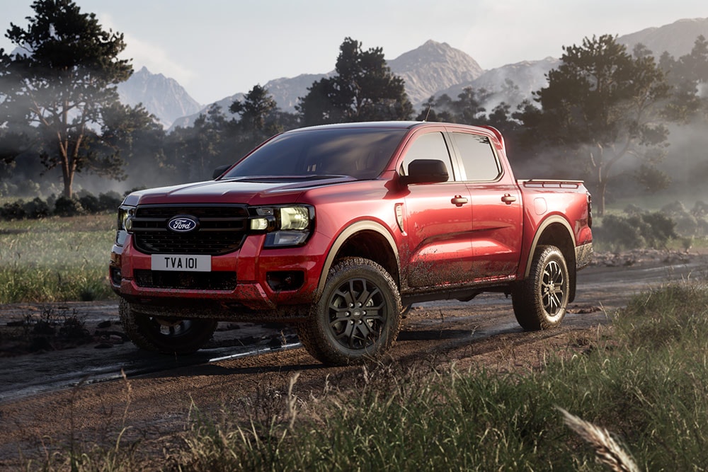 Červený Ford Ranger Raptor jedoucí po polní cestě malebnou krajinou.