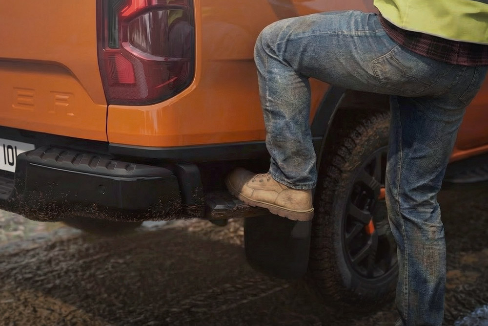 Pracovník nastupující na integrovaný zadní schůdek Fordu Ranger Wildtrak.