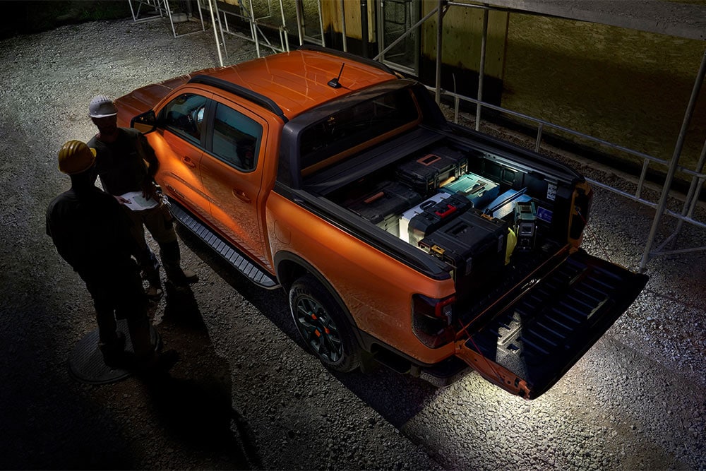 Pohled shora na oranžový Ford Ranger Wildtrak v noci s venkovním zónovým osvětlením.