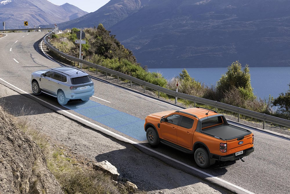 Oranžový Ford Ranger využívající pokročilý asistenční systém na dálnici podél pobřeží.
