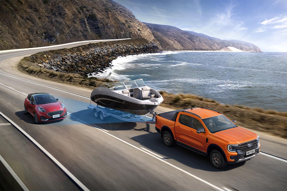 Oranžový Ford Ranger táhnoucí loď po dálnici podél pobřeží pro demonstraci tažné síly.