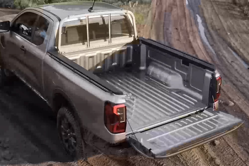 Pohled shora na stříbrný Ford Ranger XLT Super Cab zaparkovaný na blátivém povrchu s otevřenými dveřmi zavazadlového prostoru.