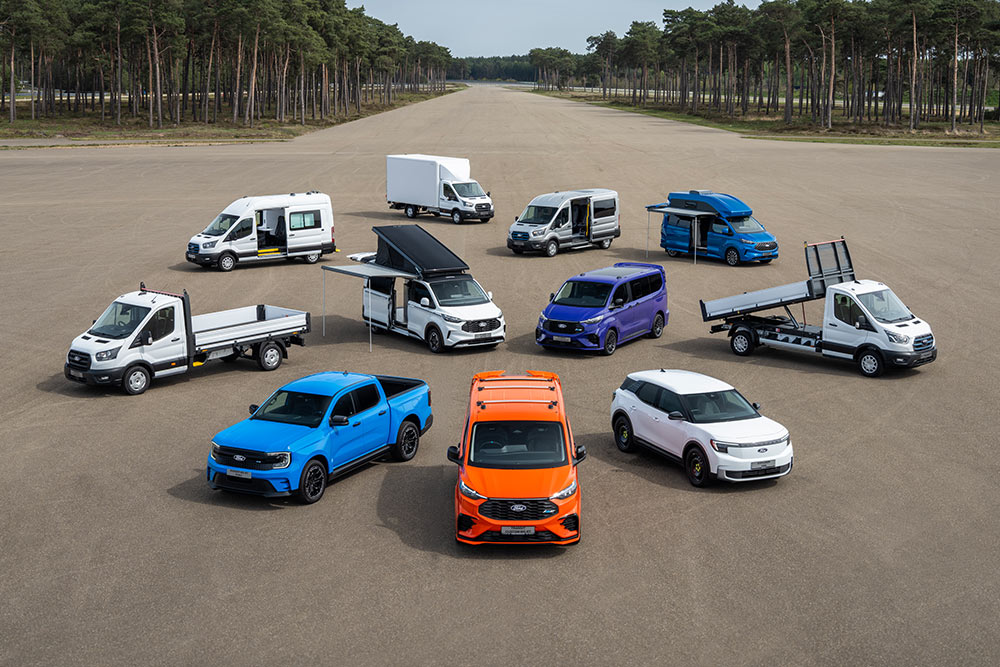 Řada užitkových vozidel Ford zaparkovaných na vozovce.